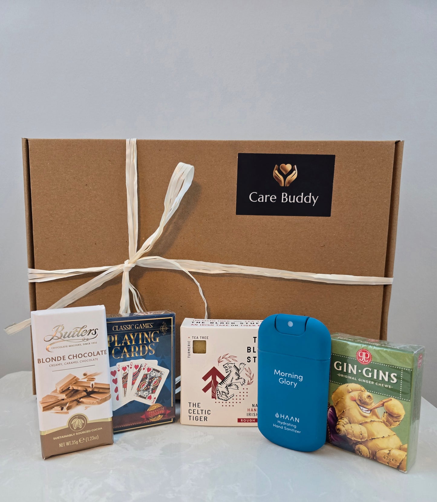 Care Buddy gift box with assorted items including chocolate, playing cards, Black Stuff Body Soap, Hydrating Hand Sanitizer and Gin Gis Ginger Chews