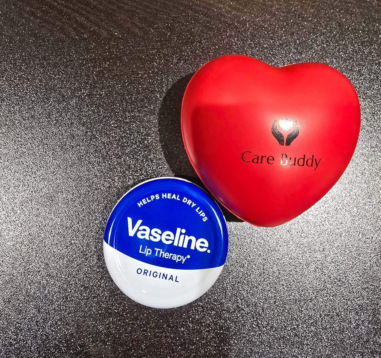 Vaseline lip therapy container and red heart-shaped 'Care Buddy' stress ball