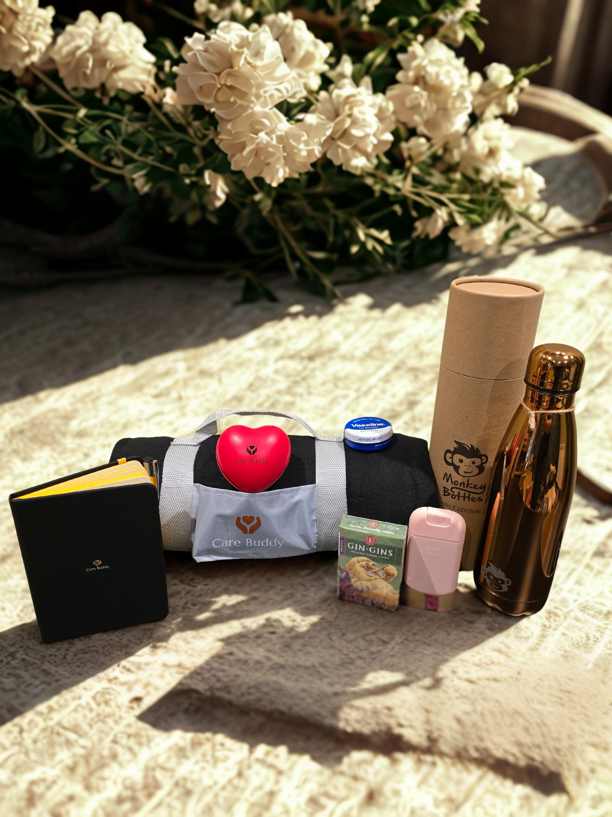 Essential Chemo Package for Hier containing cosy Fleece black blanket that rolls up into a holder, Monkey Bottle colour Rose Gold keeps drinks Cold 24hrs and Warm for 12hrs. Black Journal and Yellow Pen. Red Heart shaped Stress Ball. Gin Gin chews for Nausea. Vaseline Lip Balm. Haan Hydrating spray Hand Sanitizer
