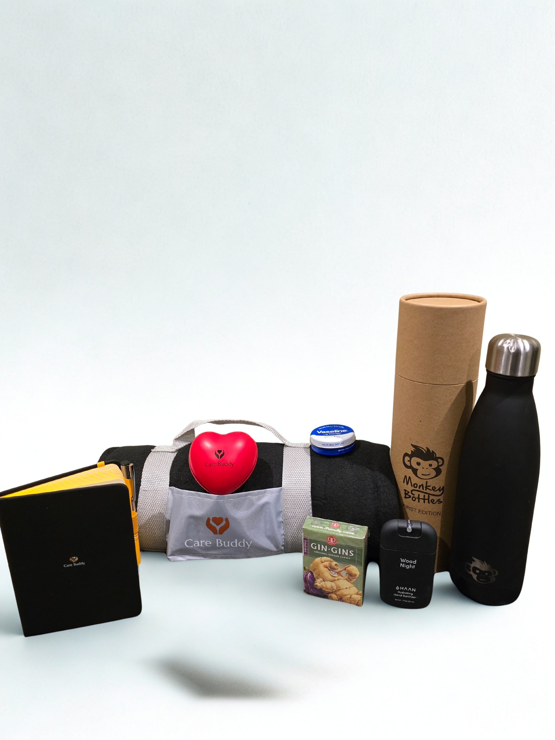 Essential Chemo Package for Him containing cosy Fleece black blanket that rolls up into a holder, Monkey Bottle colour Black keeps drinks Cold 24hrs and Warm for 12hrs. Black Journal and Yellow Pen. Red Heart shaped Stress Ball. Gin Gin chews for Nausea. Vaseline Lip Balm. Haan Hydrating spray Hand Sanitizer