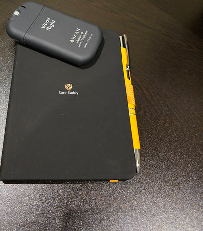 Black Journal with a yellow pen and black Wood Night Hydrating Hand Sanitizer spray
