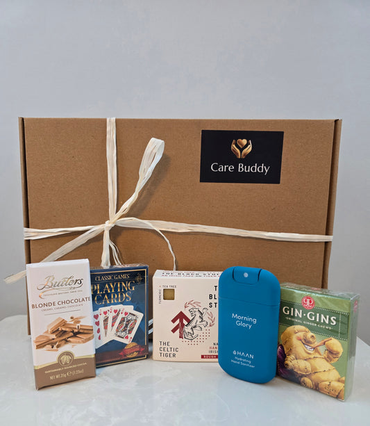 Care Buddy gift box with assorted items including chocolate, playing cards, Black Stuff Body Soap, Hydrating Hand Sanitizer and Gin Gis Ginger Chews