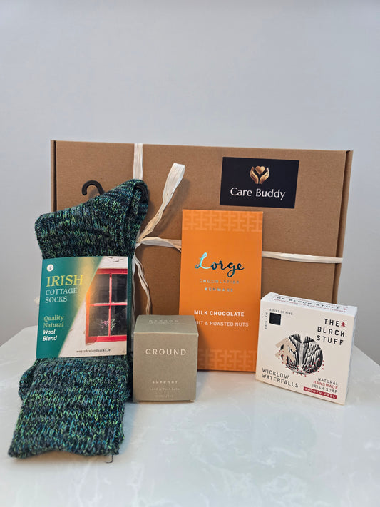 Box with care items including socks, Ground Wellbeing Hand & Foot Balm, Lorge Chocolate bar, The Black Stuff Body soap